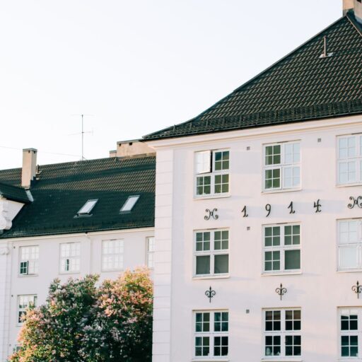 Facade of aged apartment building with white walls located in green area of town