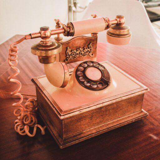 white and brown rotary telephone on brown wooden table